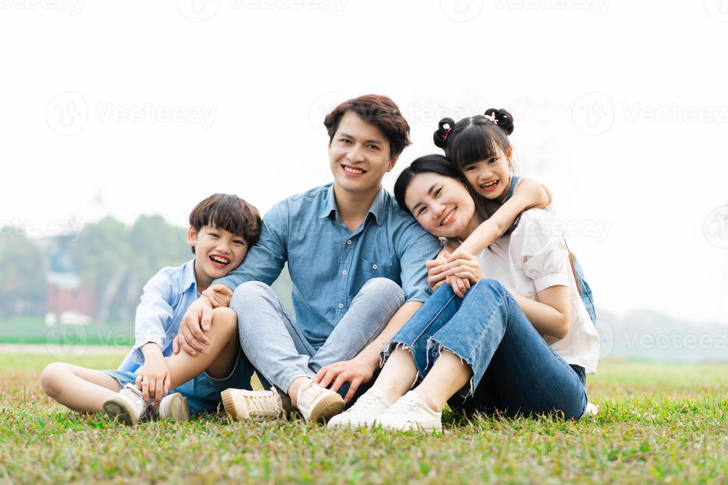 image of an asian family sitting together on the grass at the park photo