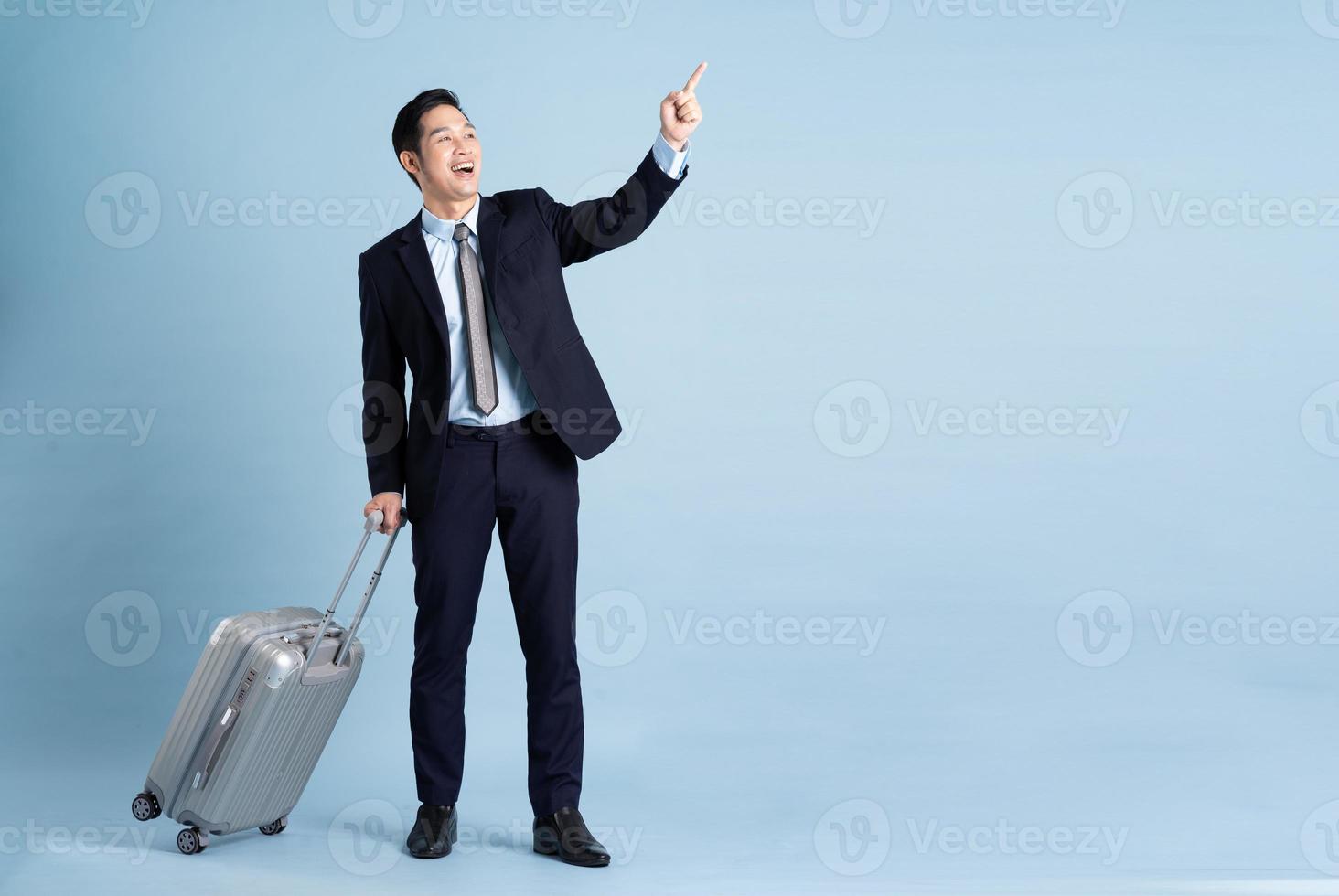 Portrait of Asian businessman wearing a suit and pulling a suitcase photo