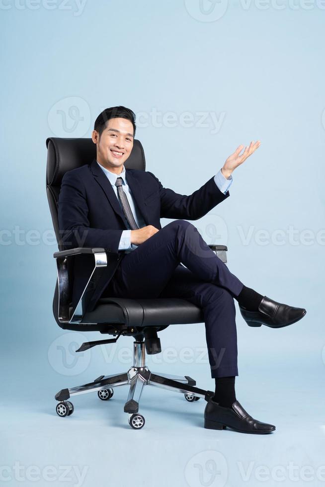 Asian businessman male portrait sitting on chair and isolated on blue background photo
