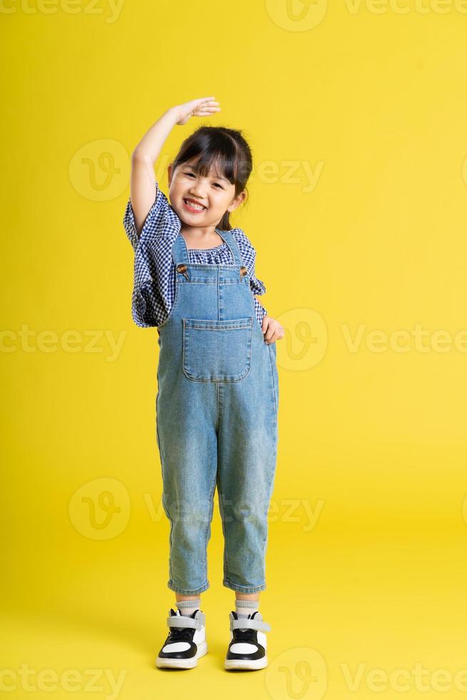 full body image of beautiful asian baby girl on yellow background photo