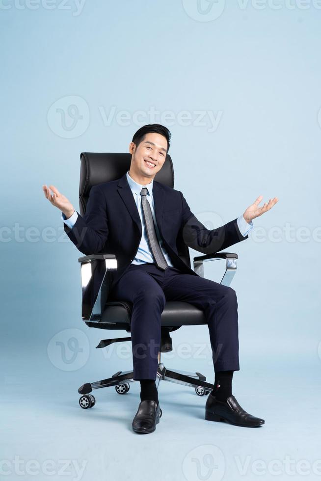 Asian businessman male portrait sitting on chair and isolated on blue background photo