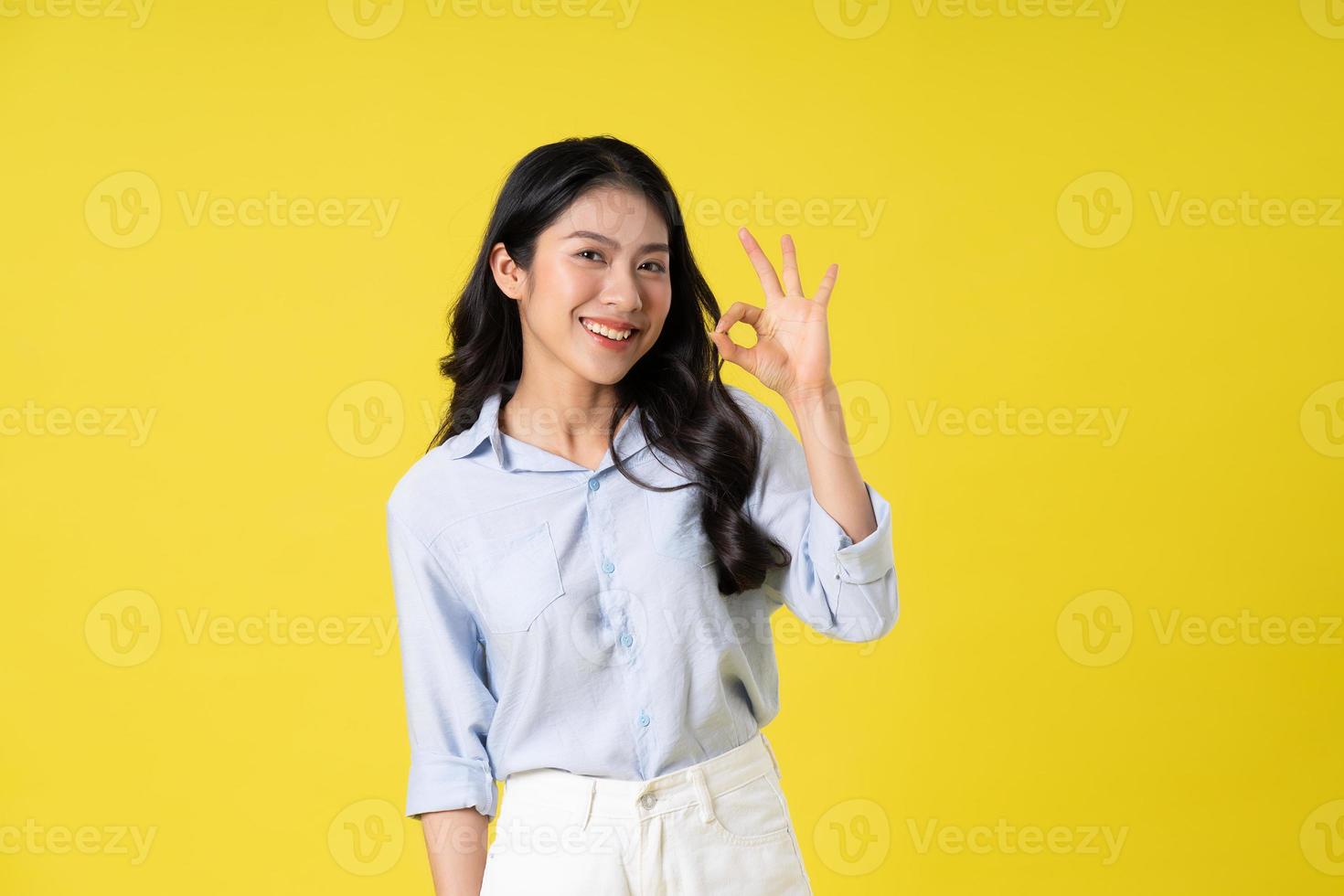 portrait of beautiful asian girl posing on yellow background photo