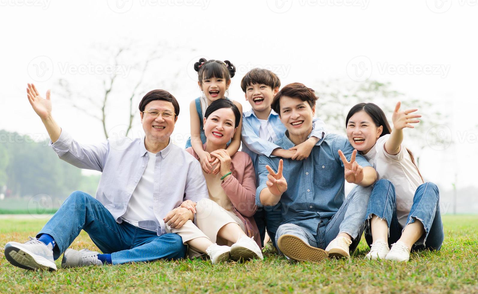 image of an asian family sitting together on the grass at the park photo