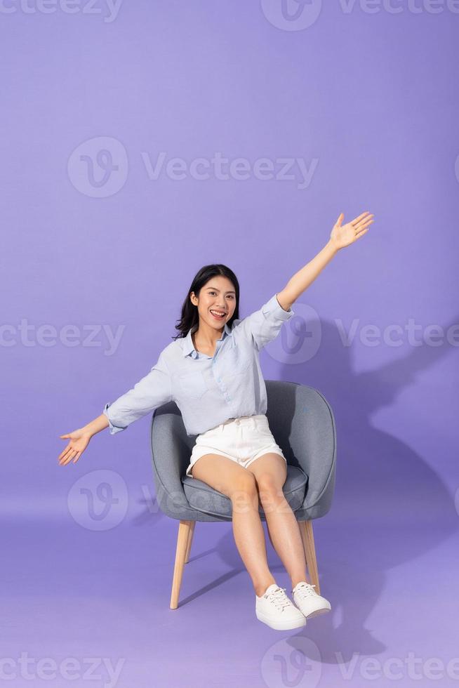 image of girl sitting on sofa  isolated on purple background photo