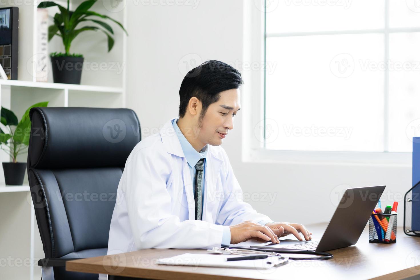 Asian male doctor portrait sitting at work photo