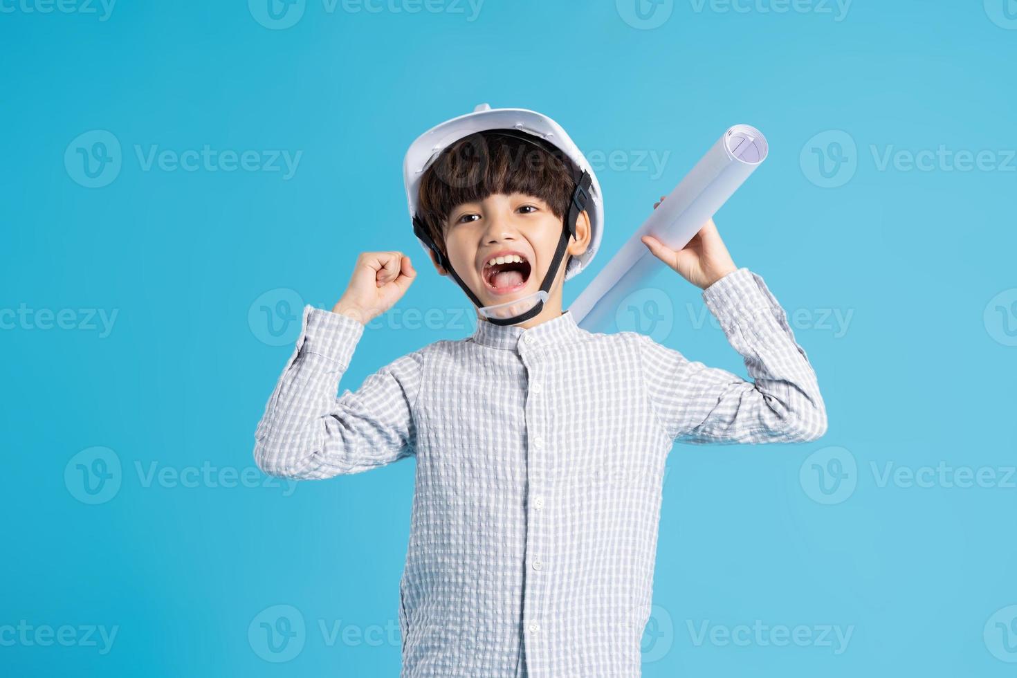 Asian boy portrait playing the role of an engineer, isolated on blue background photo