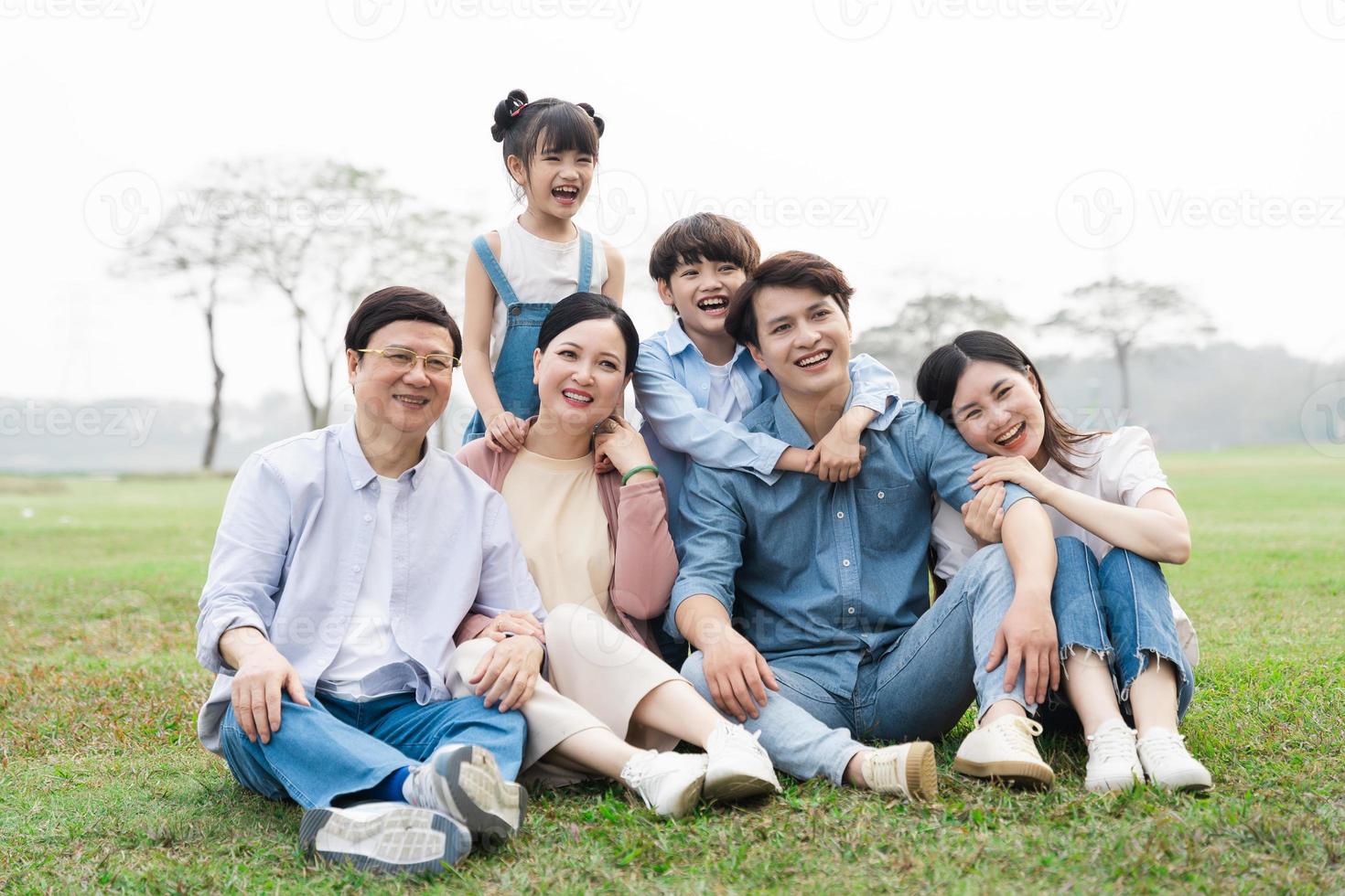 imagen de un asiático familia sentado juntos en el césped a el parque foto