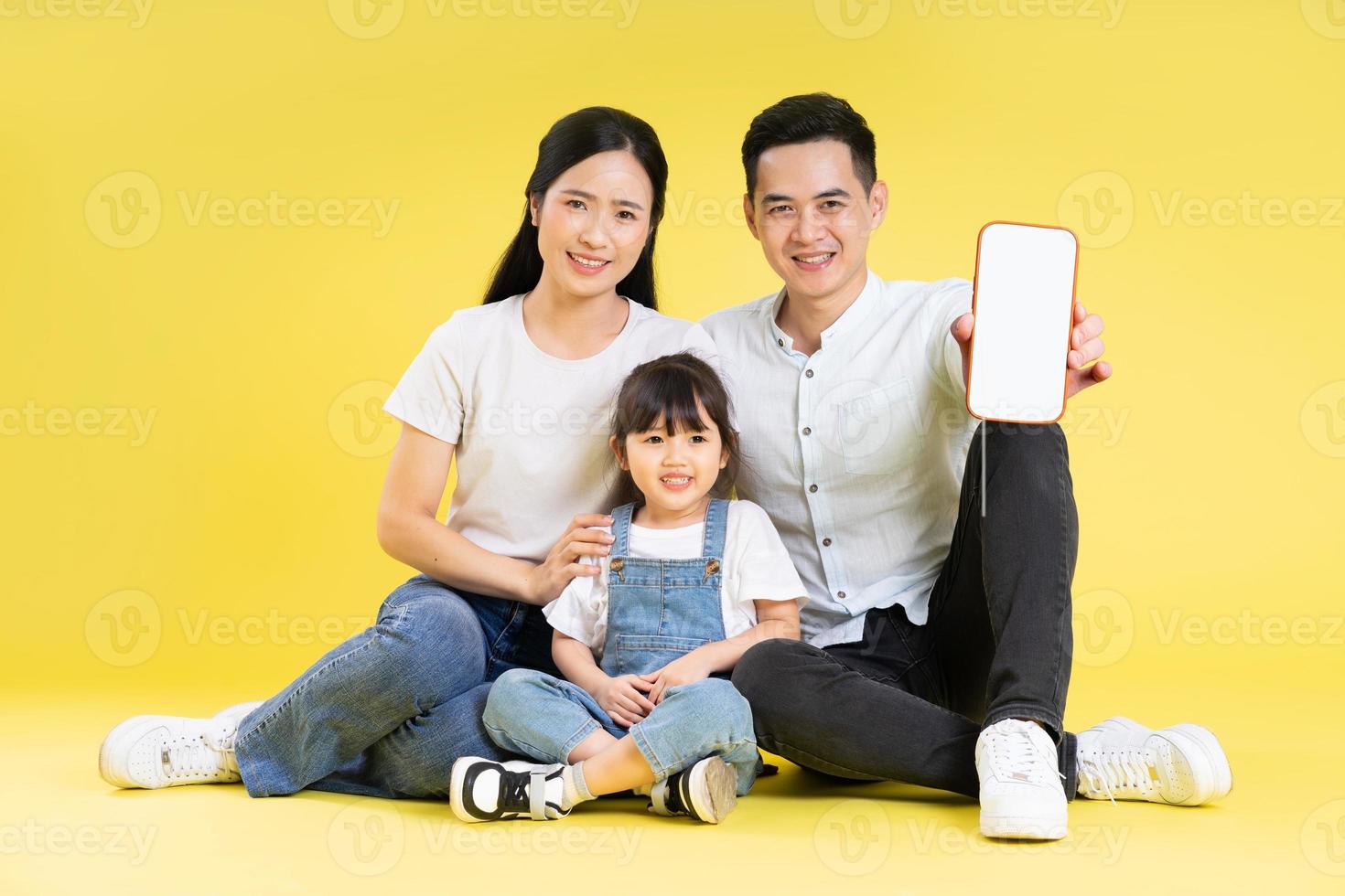 imagen de una familia asiática sentada feliz y aislada de fondo amarillo foto