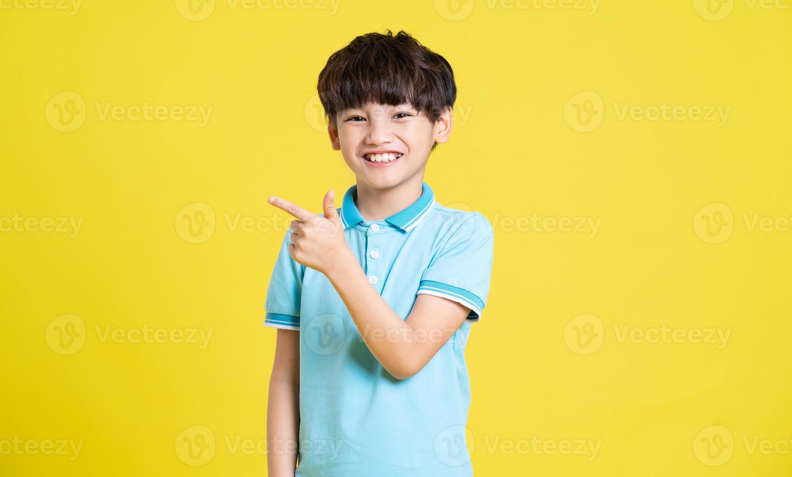 portrait of an asian boy posing on a yellow background photo