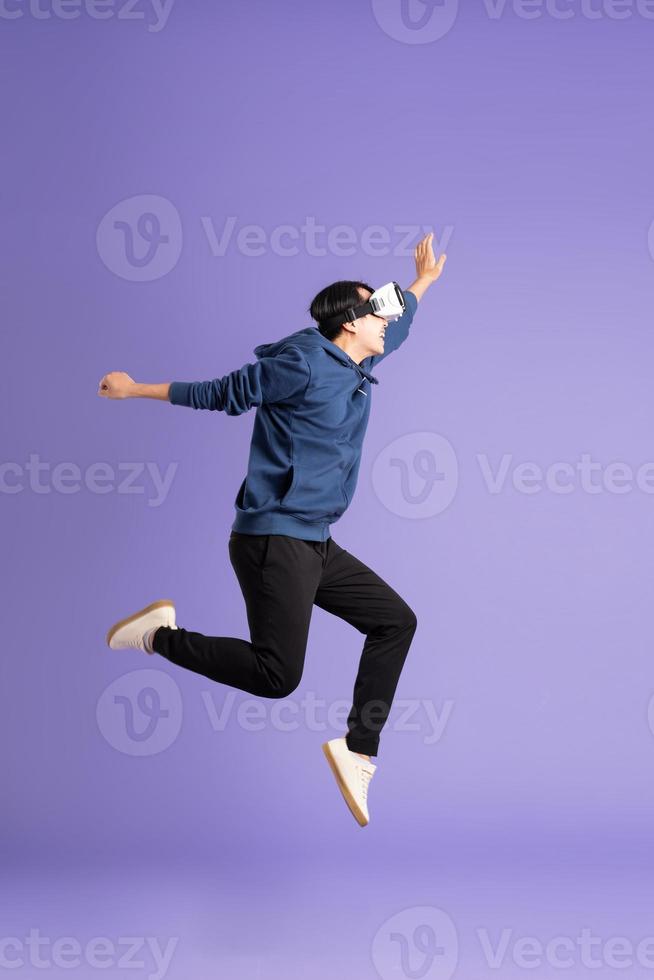 image of asian man wearing virtual reality glasses on purple background photo