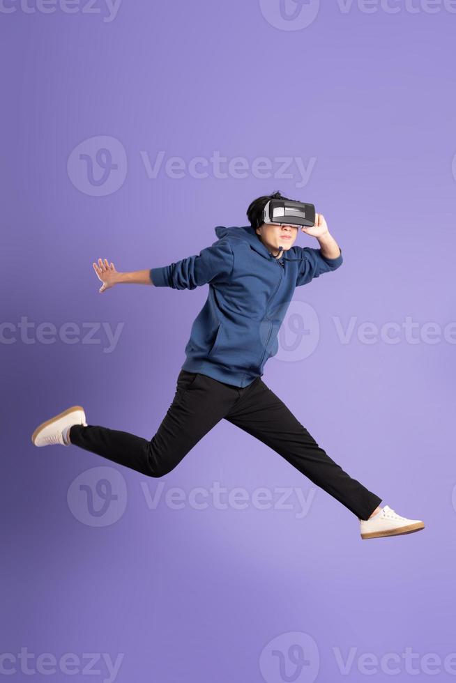 image of asian man wearing virtual reality glasses on purple background photo