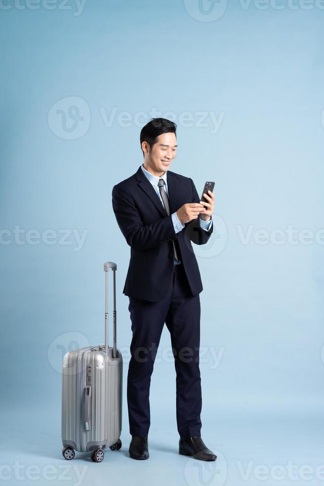 Portrait of Asian businessman wearing a suit and pulling a suitcase photo