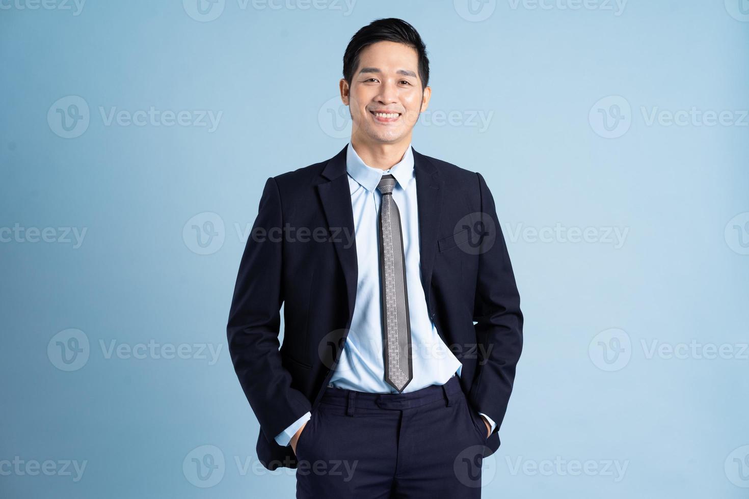 portrait of asian businessman wearing suit on blue background photo