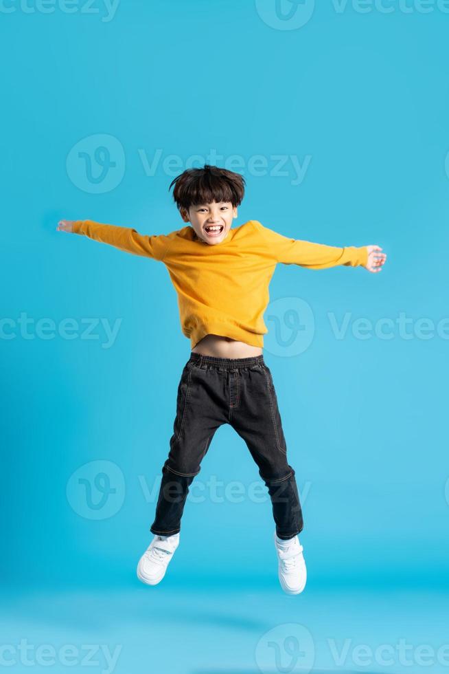 lleno cuerpo imagen de asiático chico posando en azul antecedentes foto