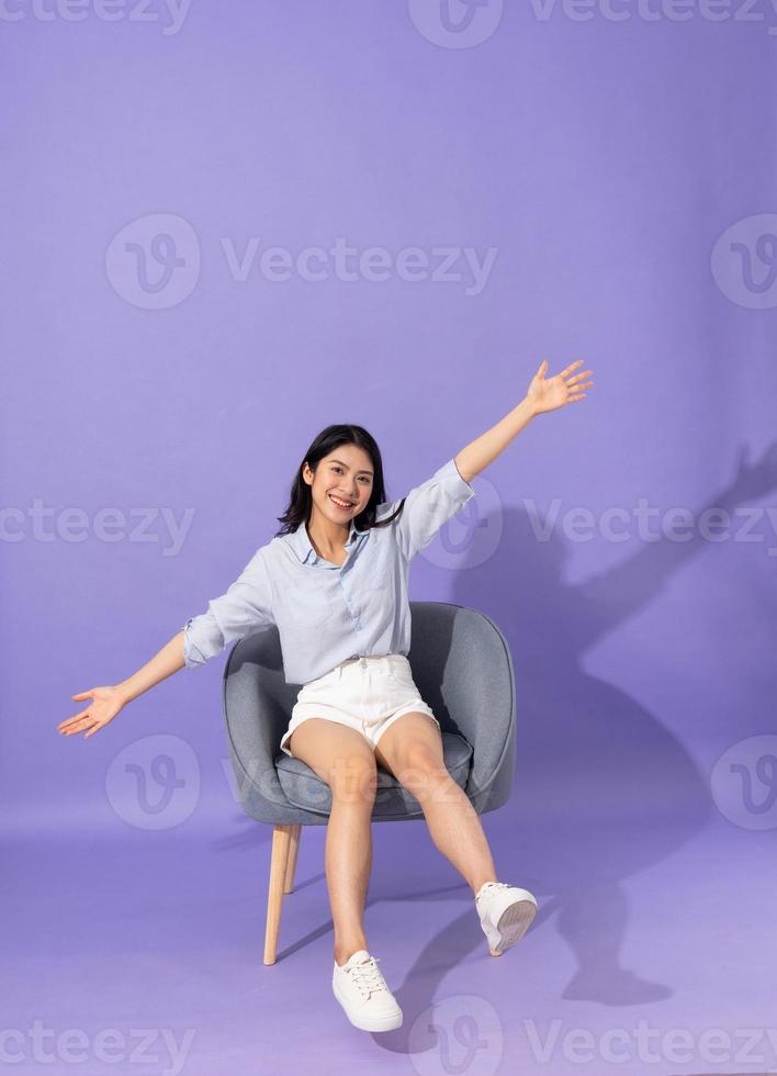 image of girl sitting on sofa  isolated on purple background photo