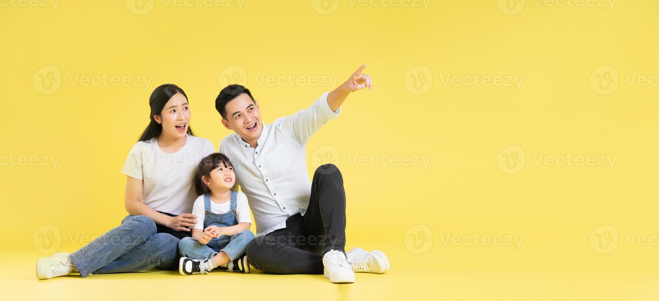 Image of Asian family sitting together happy and isolated on yellow background photo