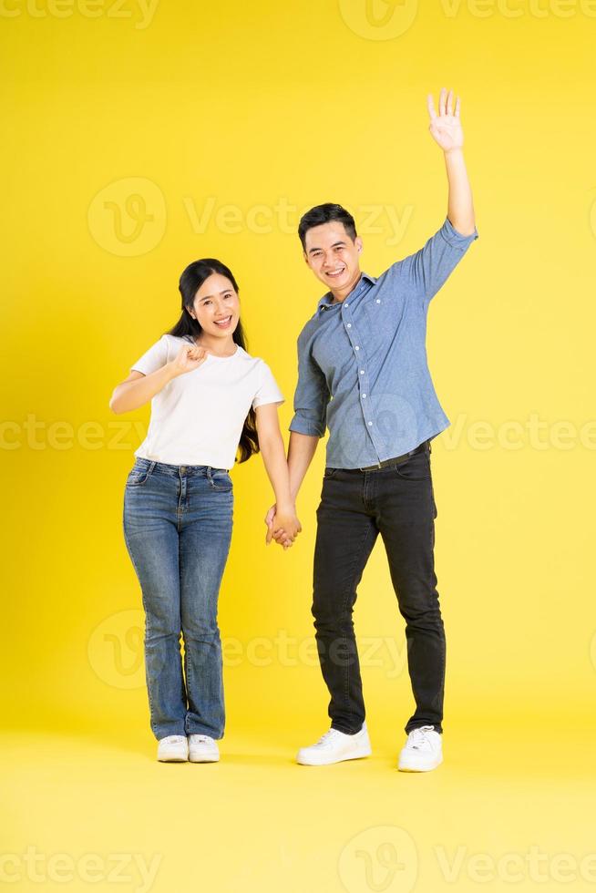 full body image of asian couple posing on yellow background photo