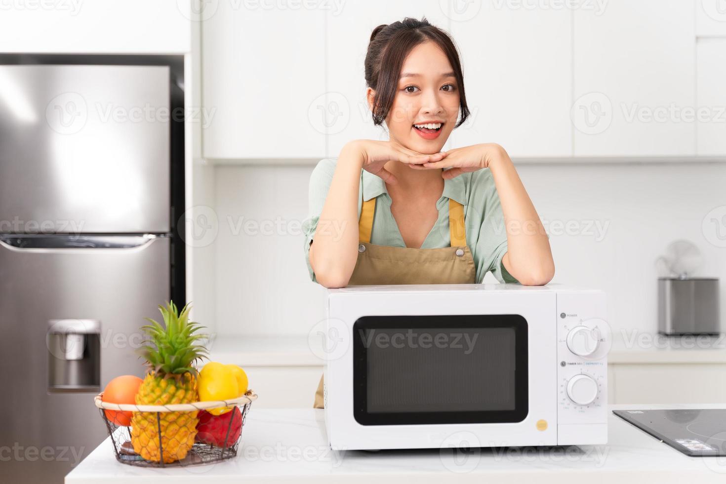 Asian girl standing next to the microwave in her kitchen photo