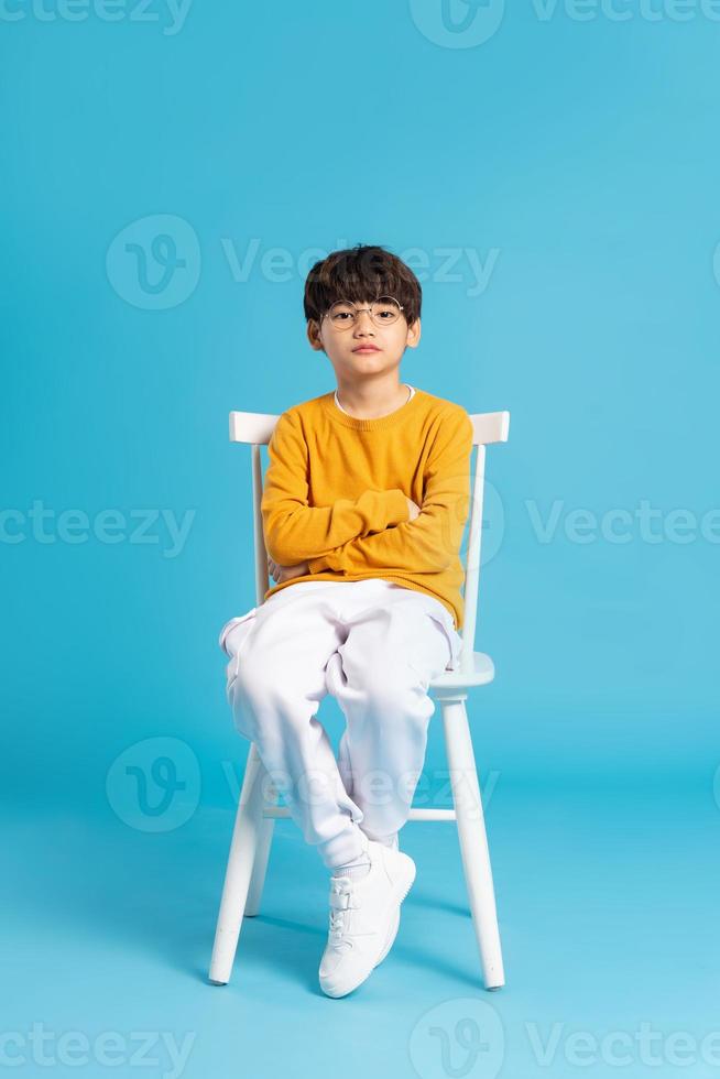 Portrait of sitting boy, isolated on blue background photo