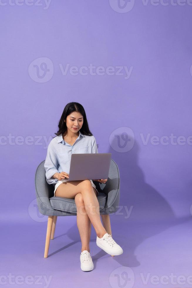 image of girl sitting on sofa  isolated on purple background photo