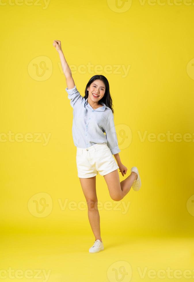 full body image of beautiful asian girl, isolated on yellow background photo