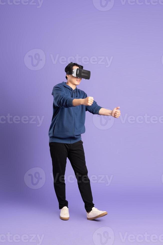 image of asian man wearing virtual reality glasses on purple background photo