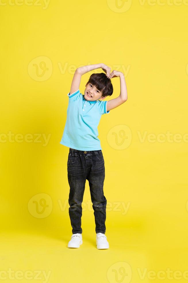 full body image of asian boy posing on yellow background photo