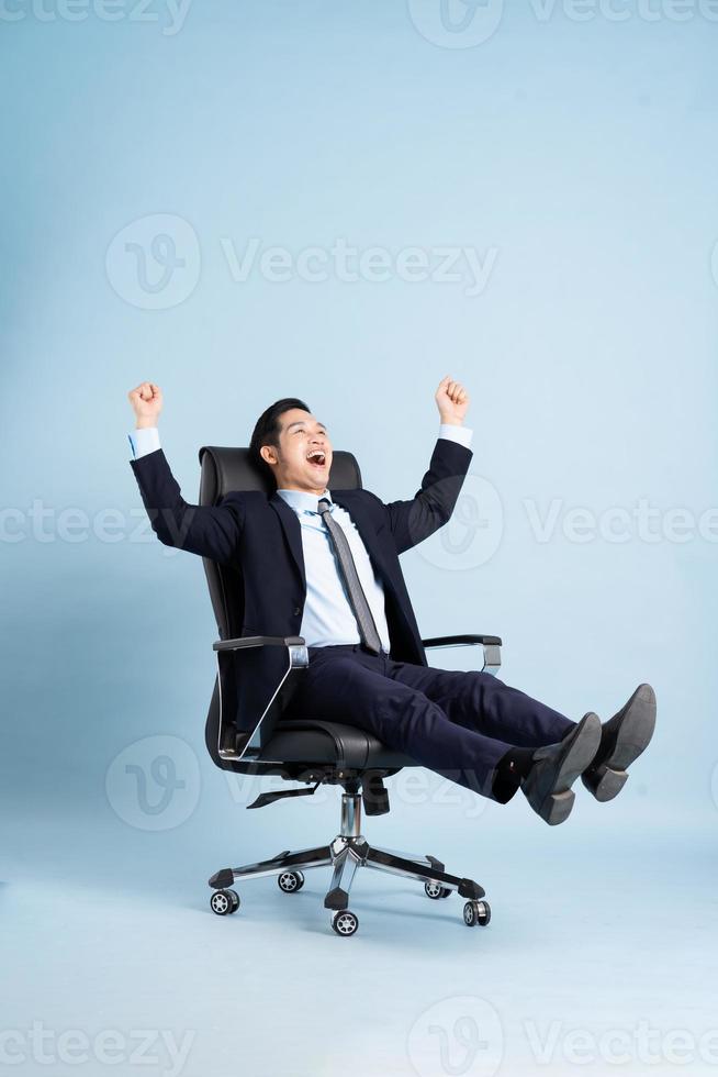 Asian businessman male portrait sitting on chair and isolated on blue background photo