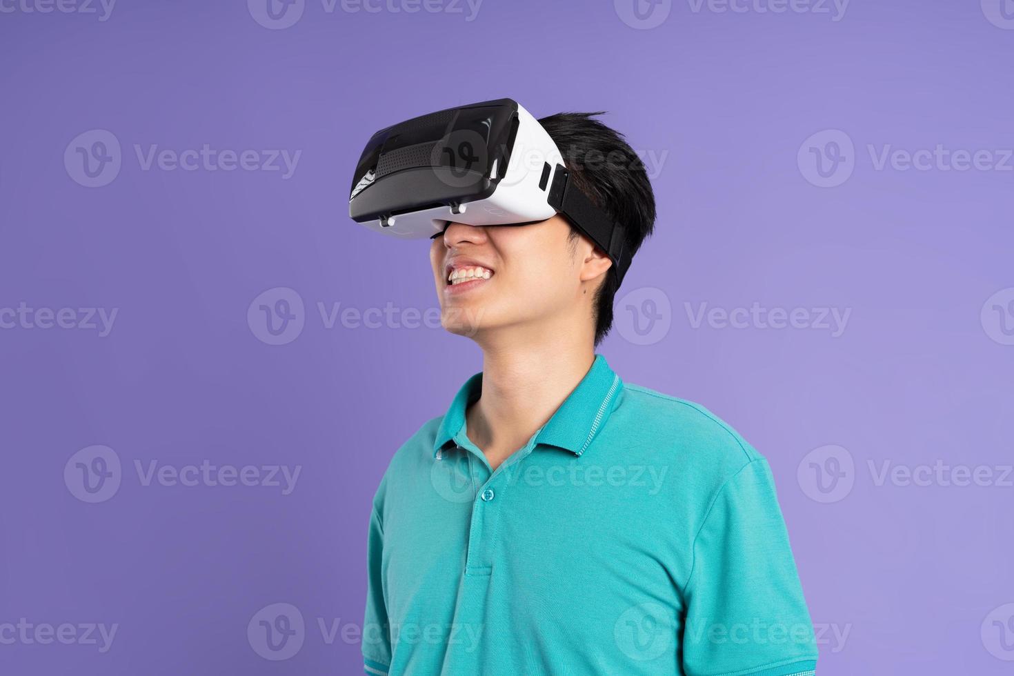 image of asian man wearing virtual reality glasses on purple background photo