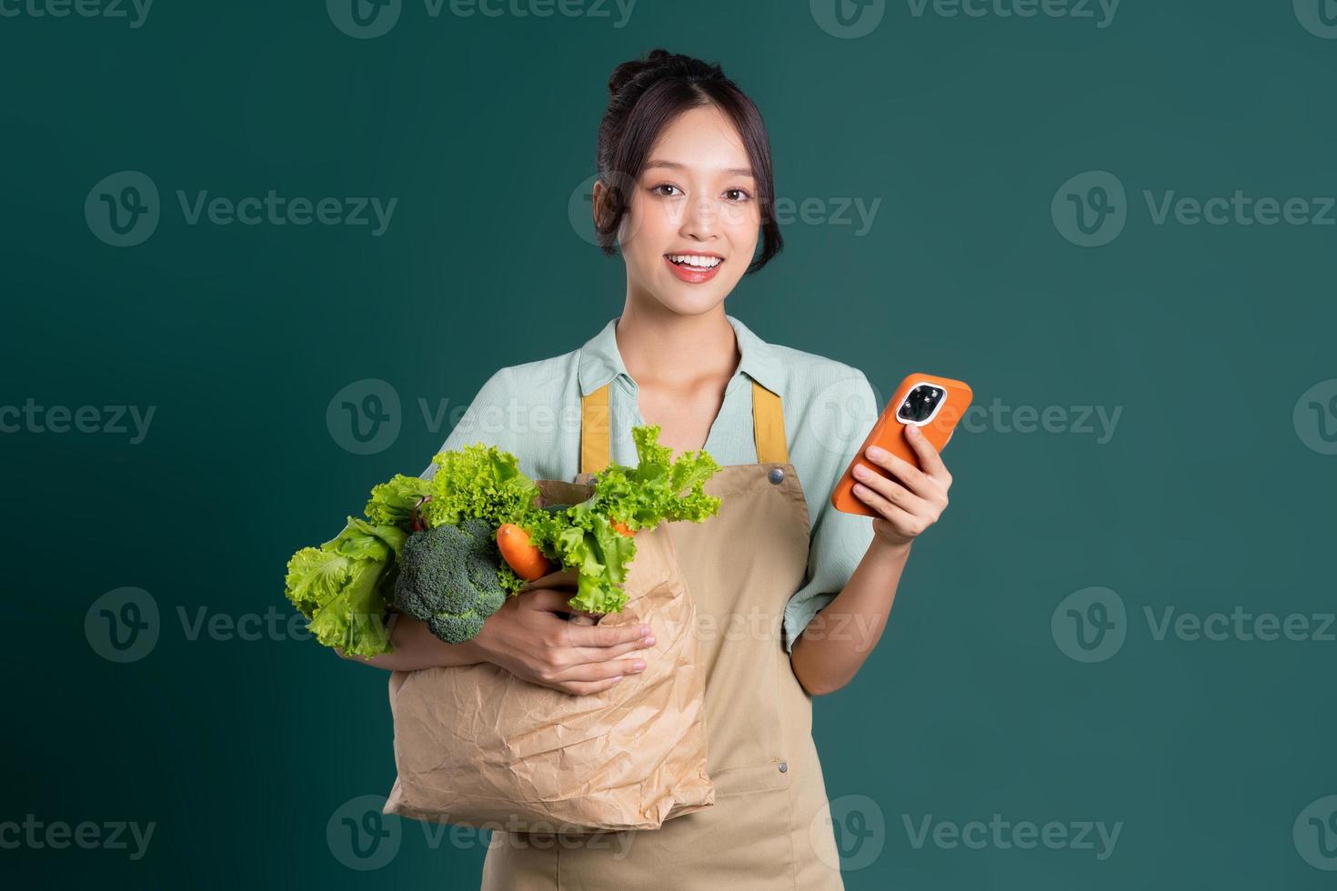 Asian girl portrait holding a bag of vegetables on a green background photo