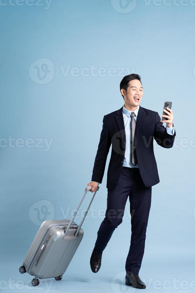 Portrait of Asian businessman wearing a suit and pulling a suitcase photo