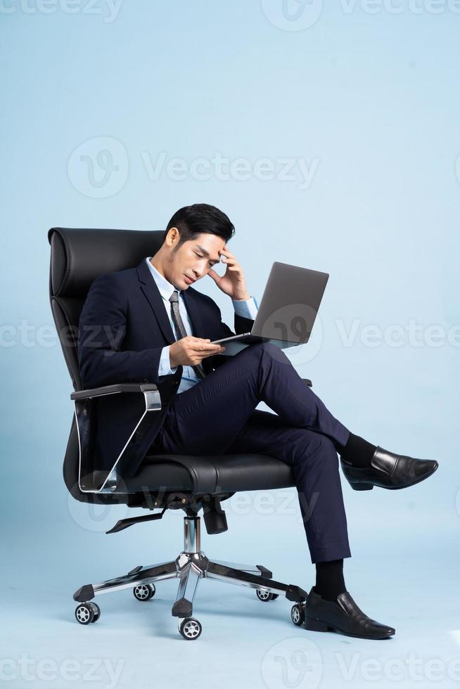 Asian businessman male portrait sitting on chair and isolated on blue background photo