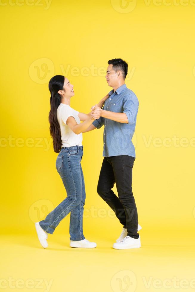 full body image of asian couple posing on yellow background photo