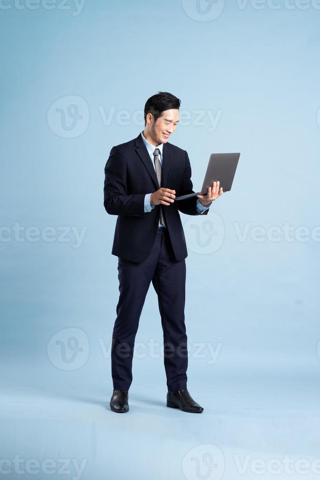 portrait of asian businessman wearing suit on blue background photo