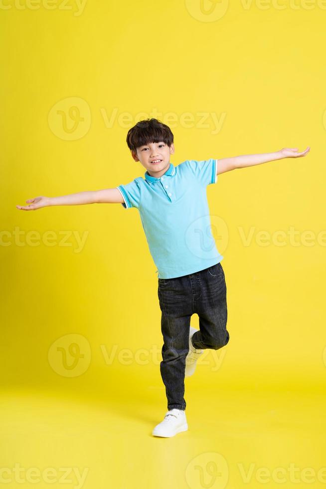 lleno cuerpo imagen de asiático chico posando en amarillo antecedentes foto