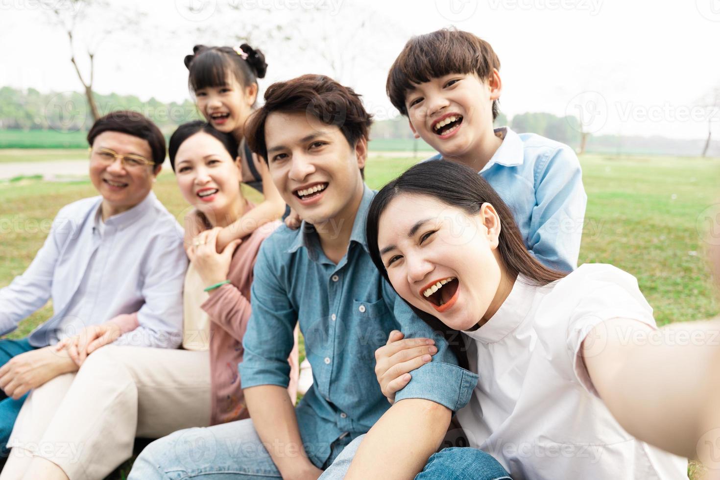 imagen de un asiático familia sentado juntos en el césped a el parque foto