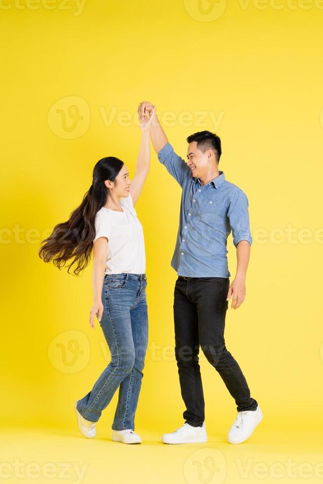 full body image of asian couple posing on yellow background photo