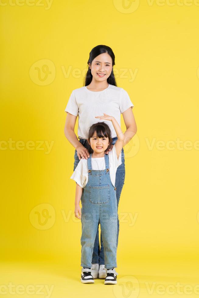 image of asian mother and daughter posing on a yellow background photo