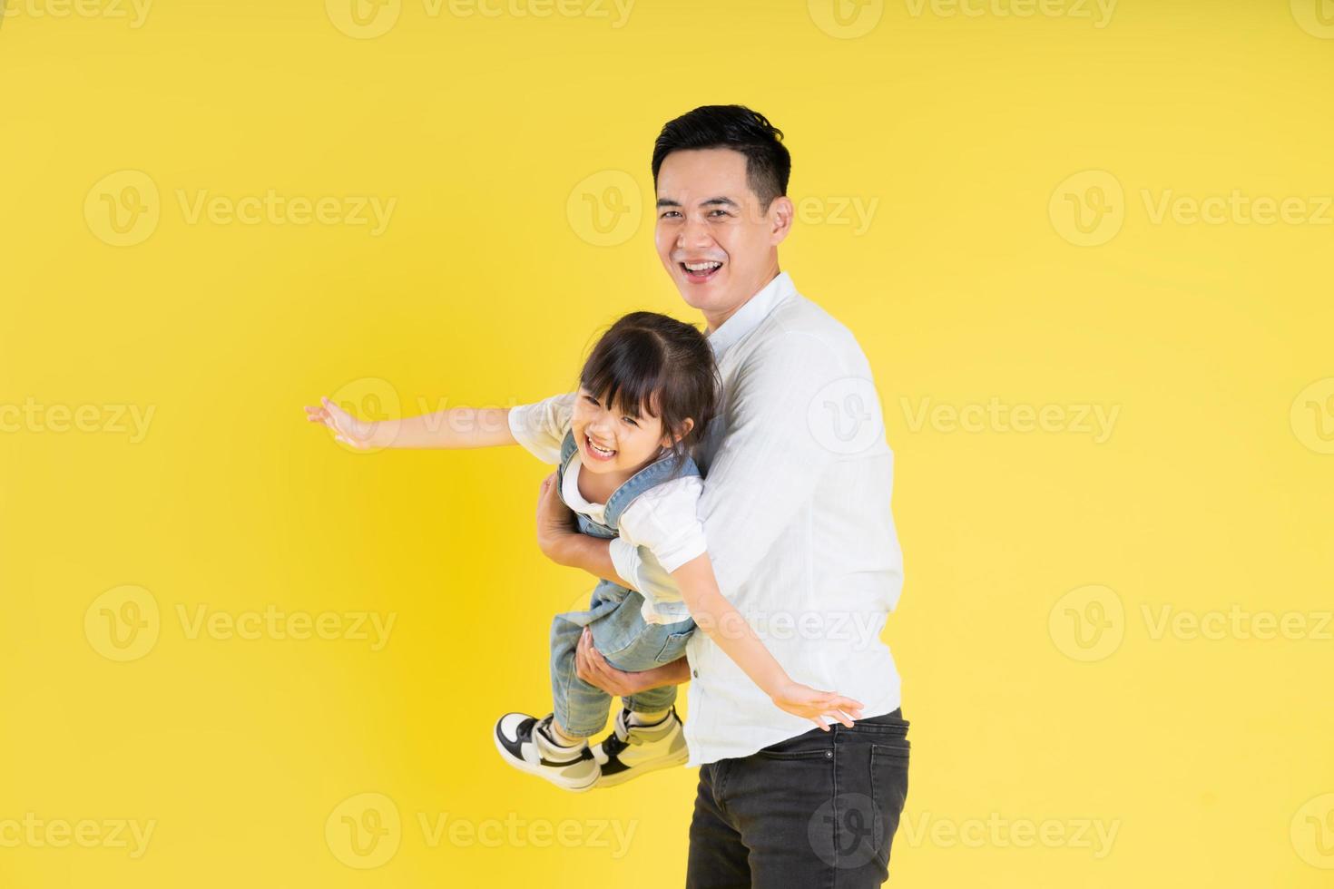 image of two happy father and daughter playing, isolated on yellow background photo
