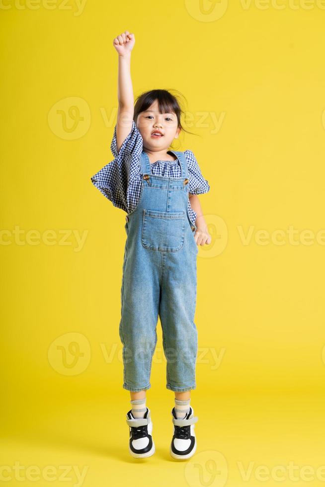 full body image of beautiful asian baby girl on yellow background photo
