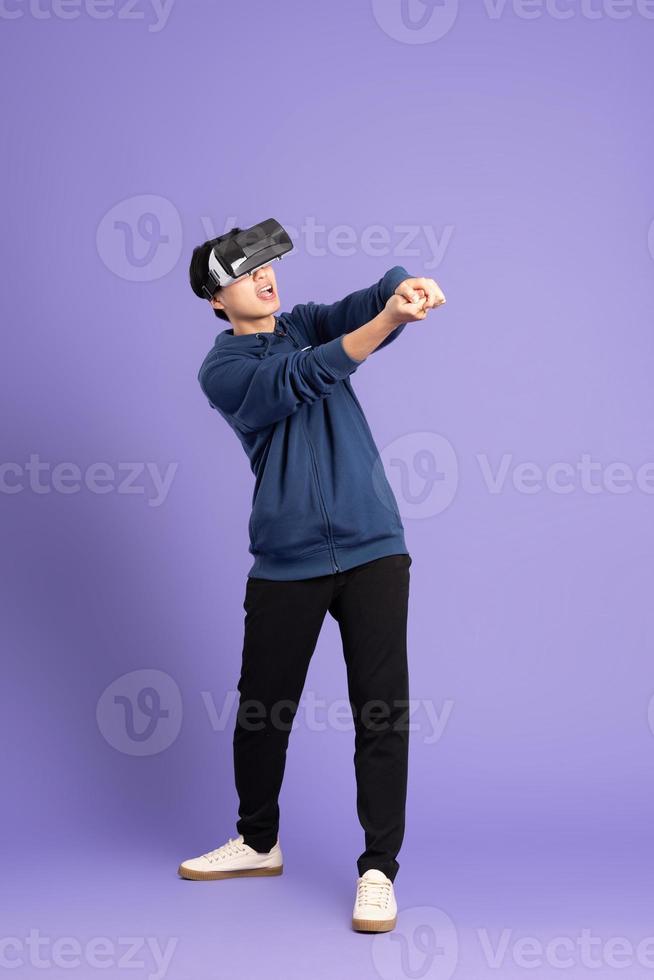 image of asian man wearing virtual reality glasses on purple background photo