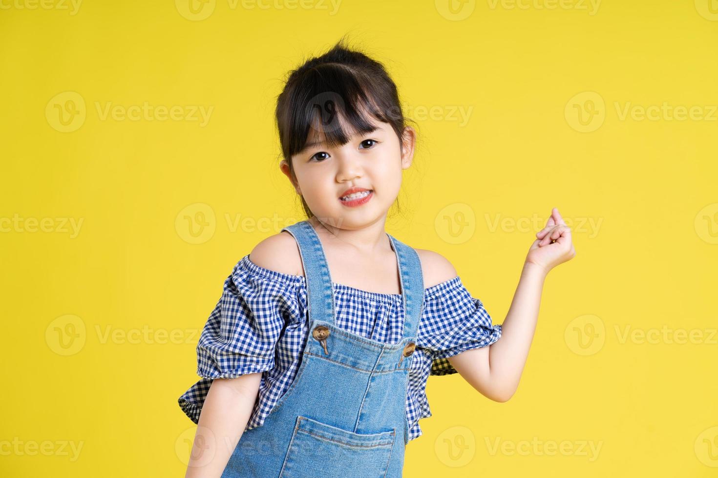 portrait of a beautiful asian girl, isolated on yellow background photo