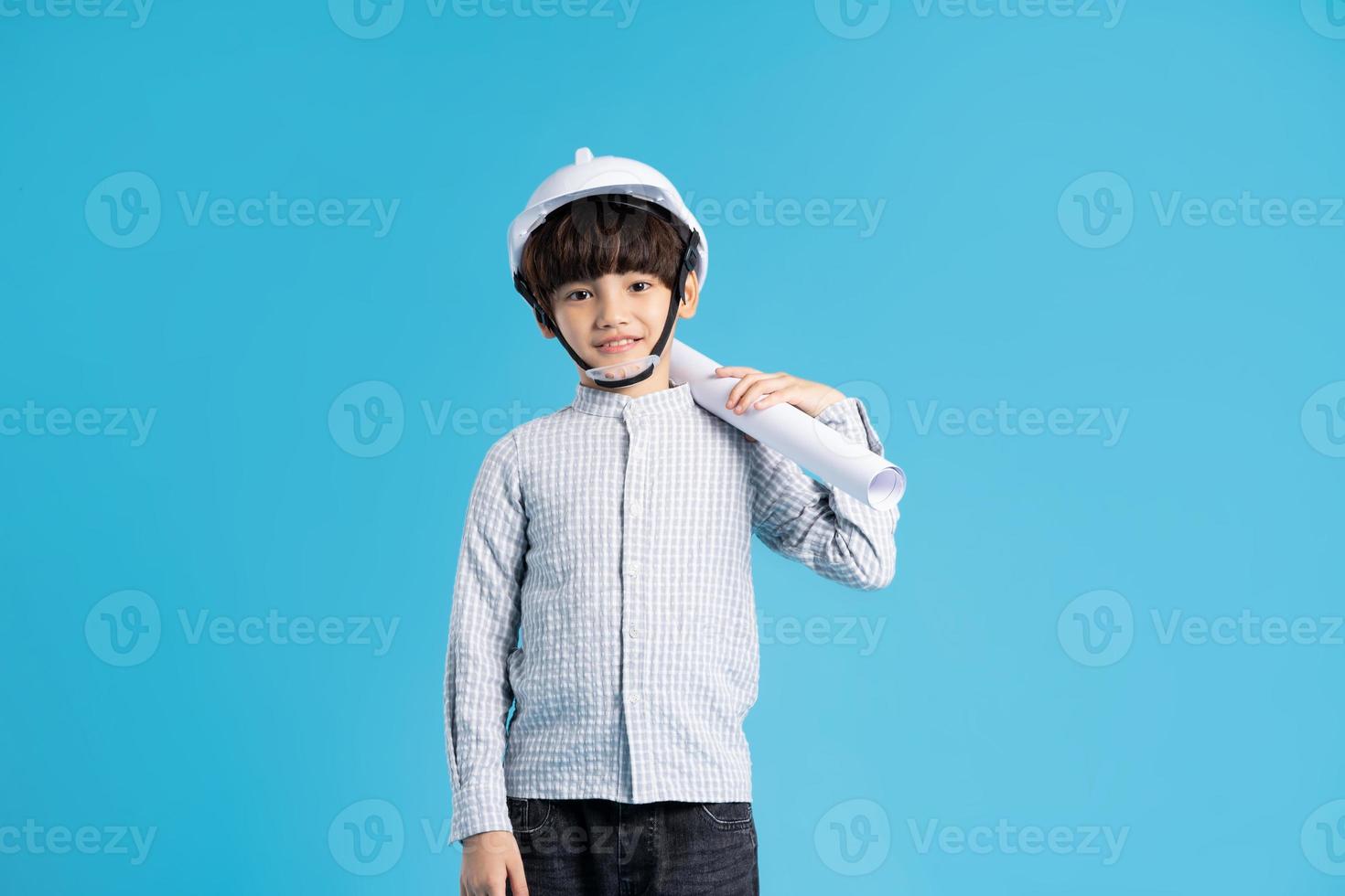 Asian boy portrait playing the role of an engineer, isolated on blue background photo