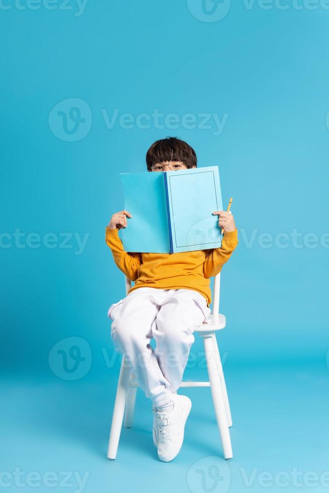 Portrait of sitting boy, isolated on blue background photo