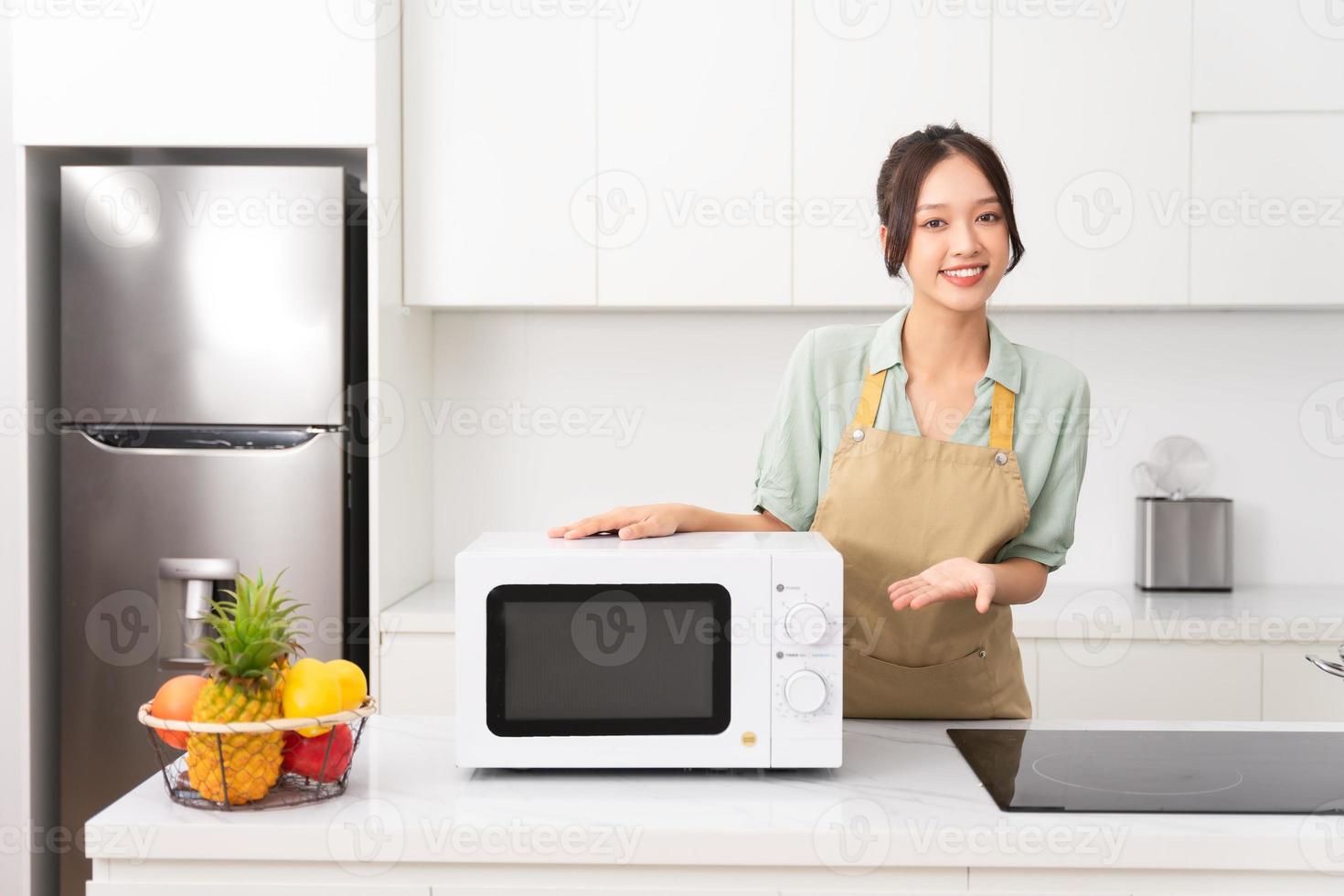 Asian girl standing next to the microwave in her kitchen photo
