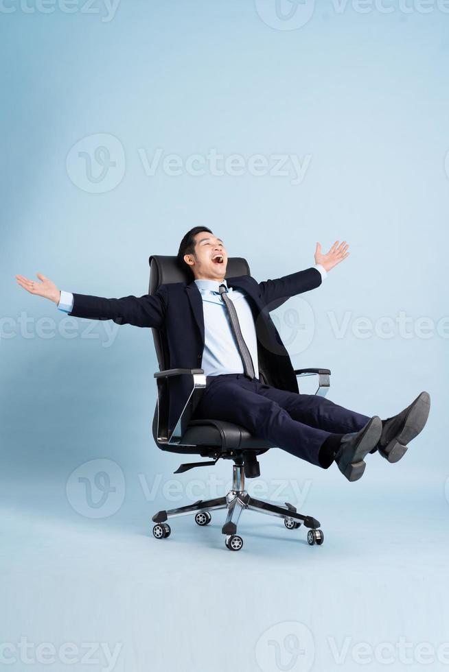 Asian businessman male portrait sitting on chair and isolated on blue background photo