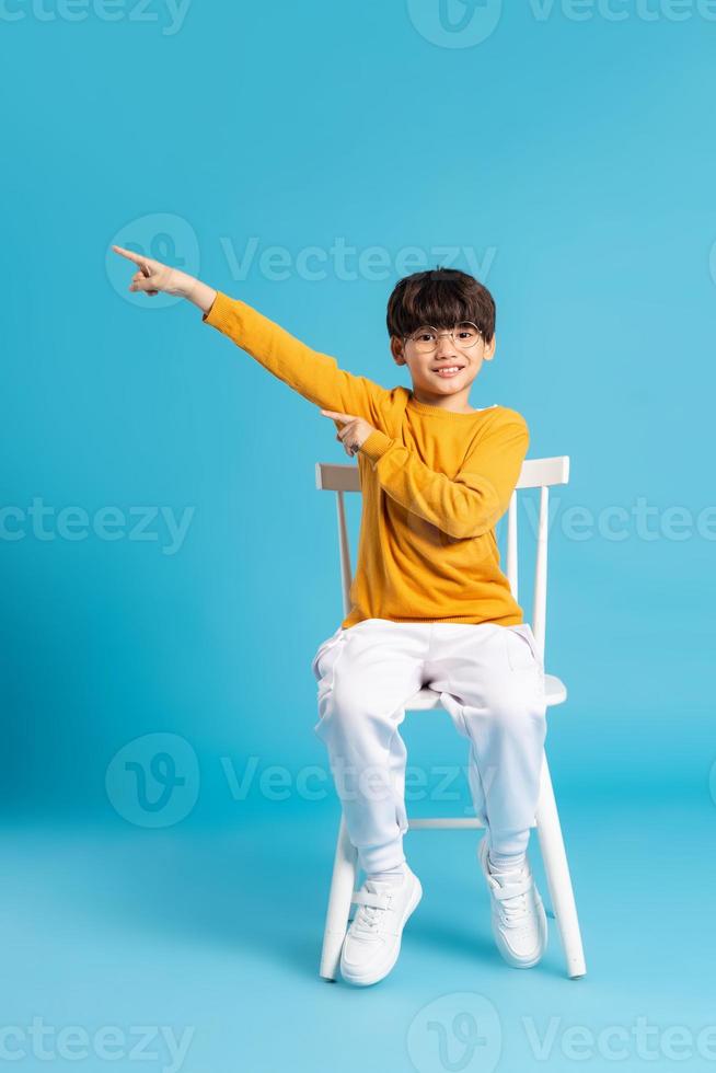 Portrait of sitting boy, isolated on blue background photo