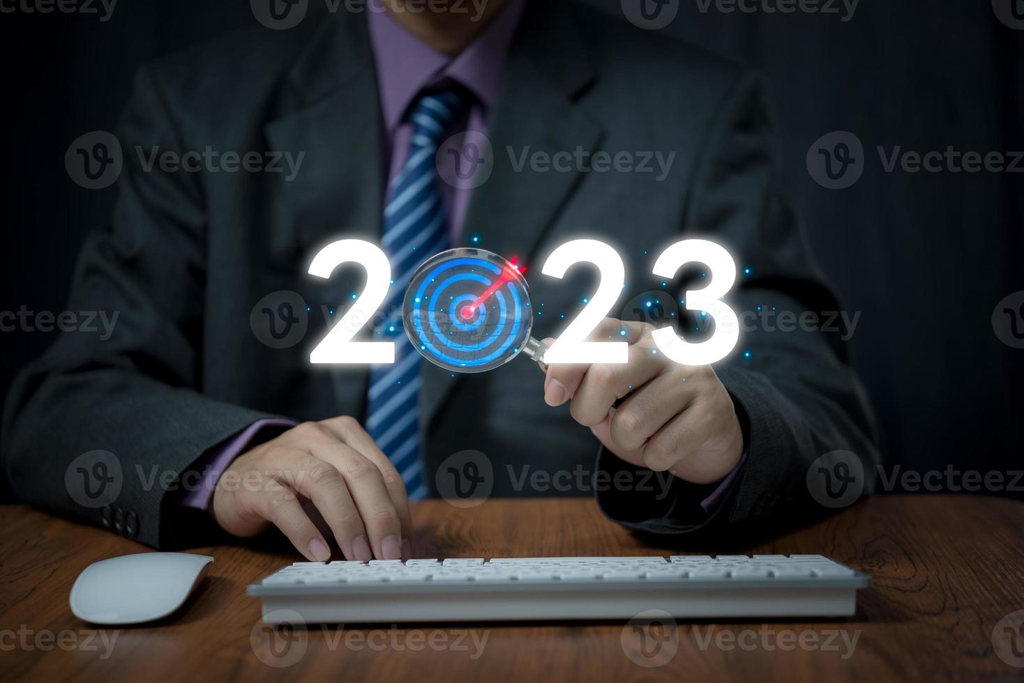 businessman holding magnifying glass to 2023 for preparation happy new year concept. new business in new years, start up, action plan and strategy in new business. photo