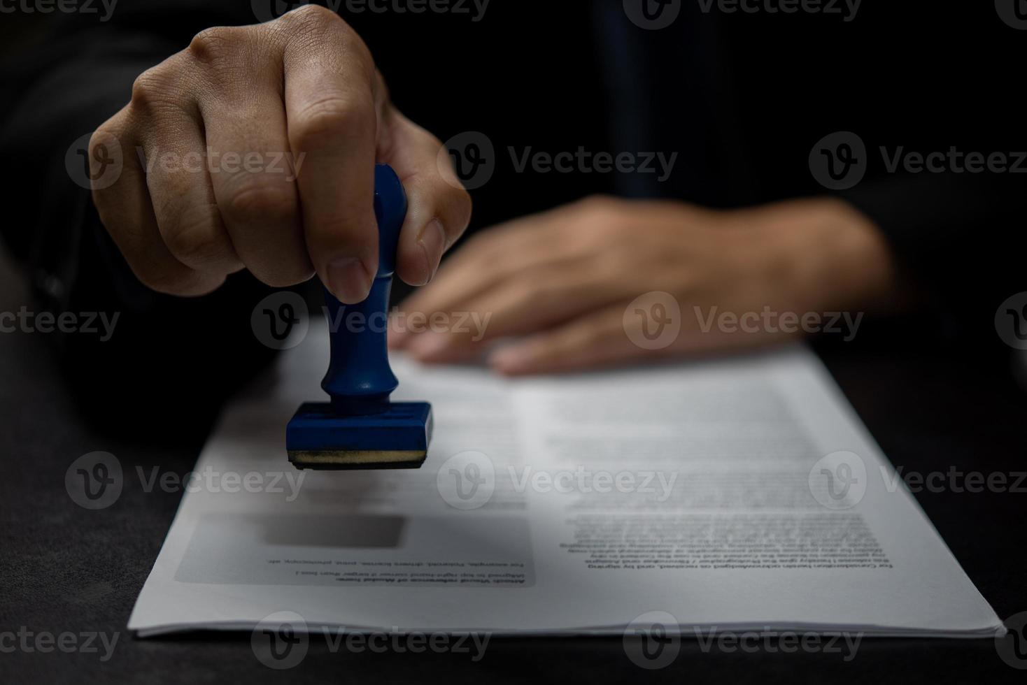 Man stamping approval of work finance banking or investment marketing documents on desk. photo