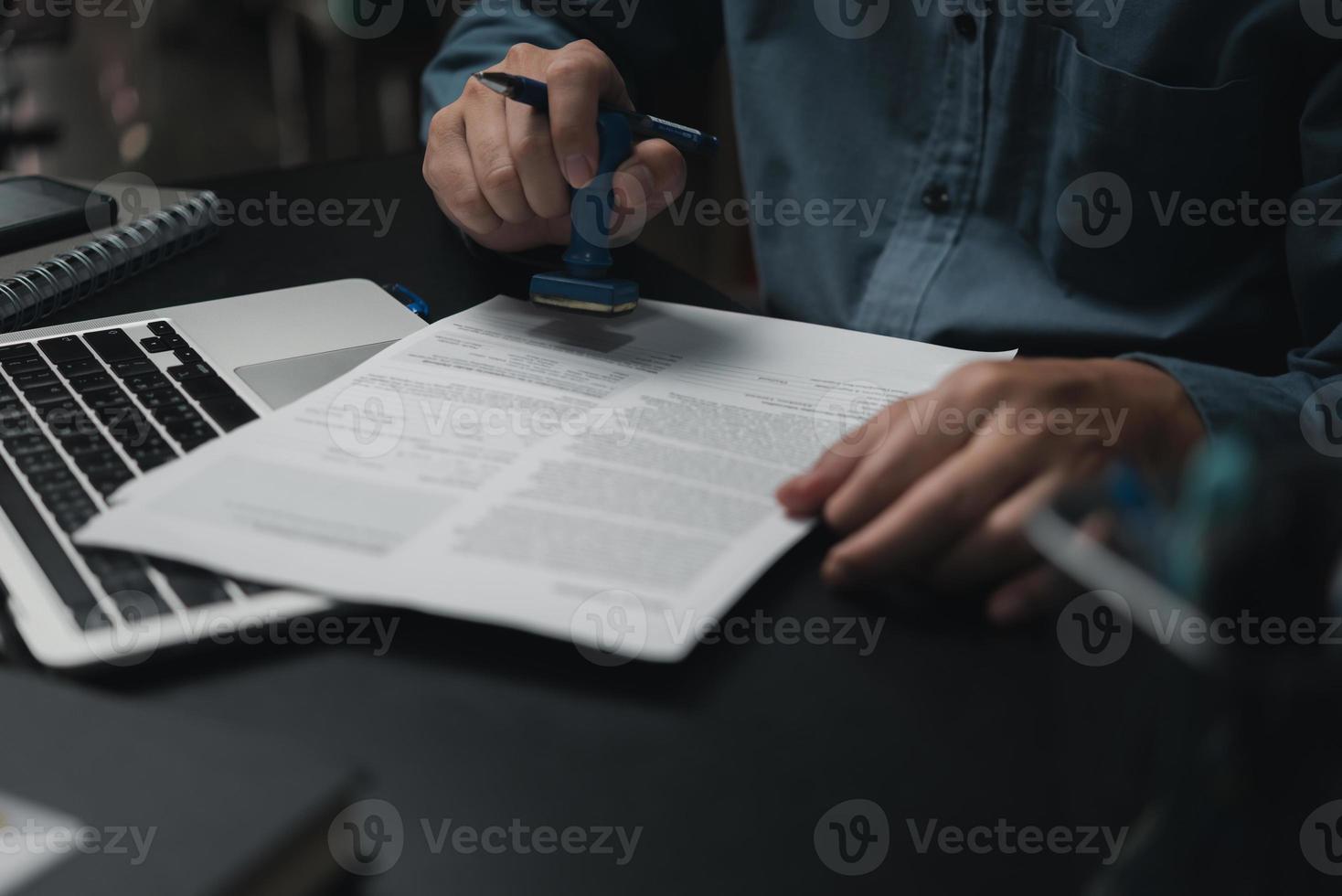 Man stamping approval of work finance banking or investment marketing documents on desk. photo